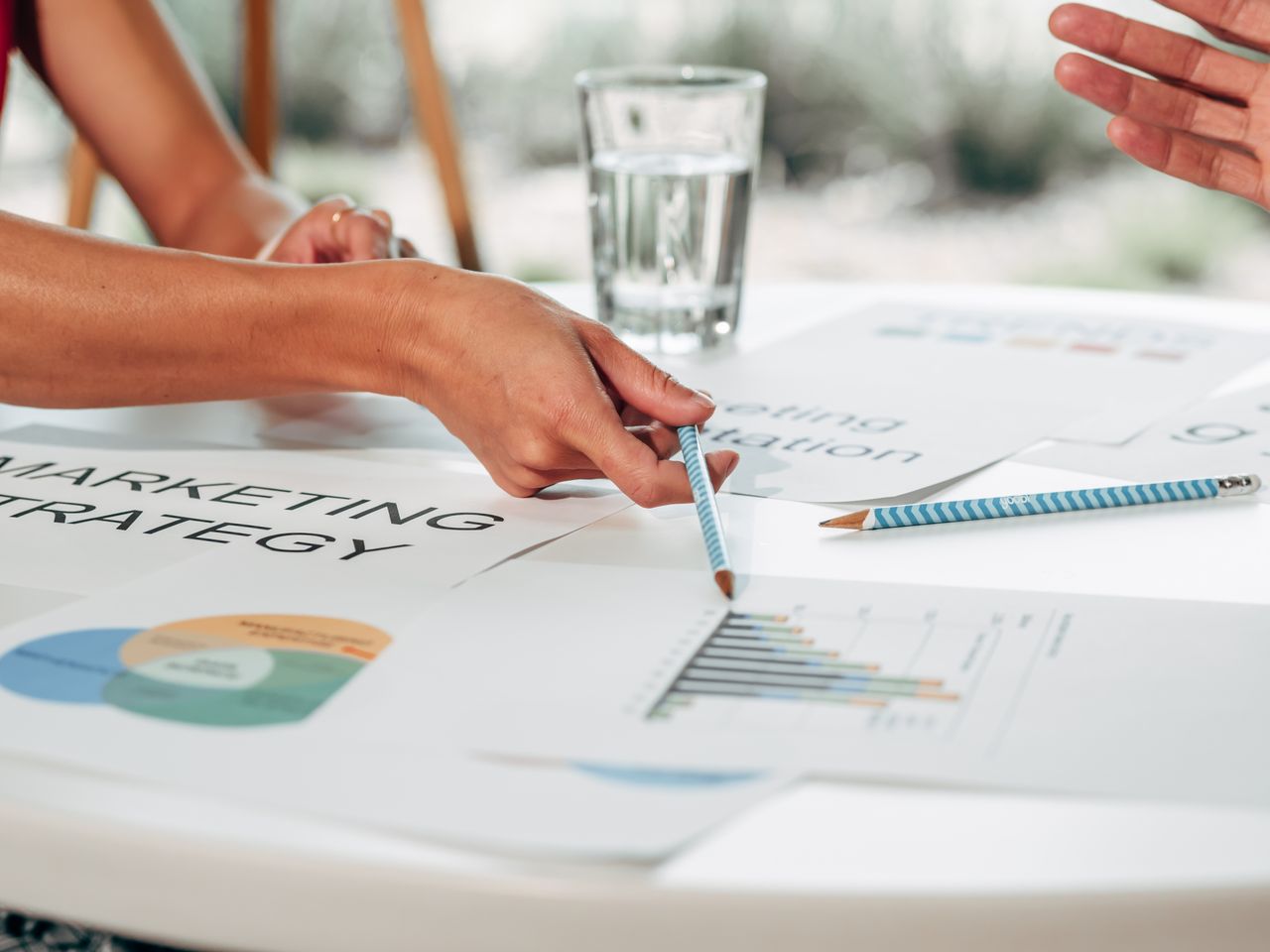 Hands reviewing a marketing strategy with charts in an office environment.